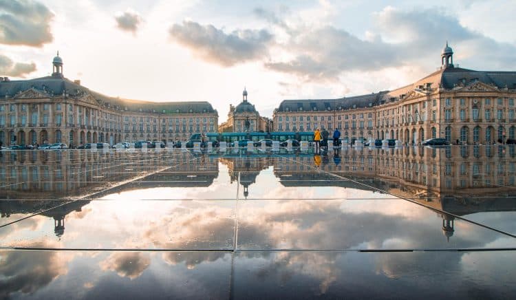 Breathtaking sunset reflection at Place de la Bourse, Bordeaux, France, showcasing historic architecture.