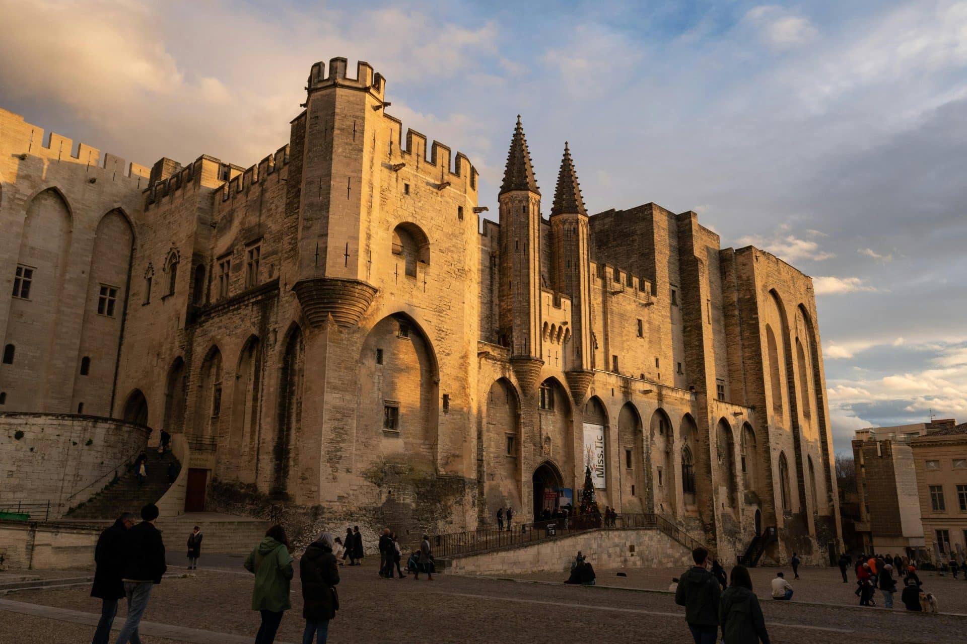 Iconic Palais des Papes in Avignon, bathed in golden sunset light, captures medieval architecture.